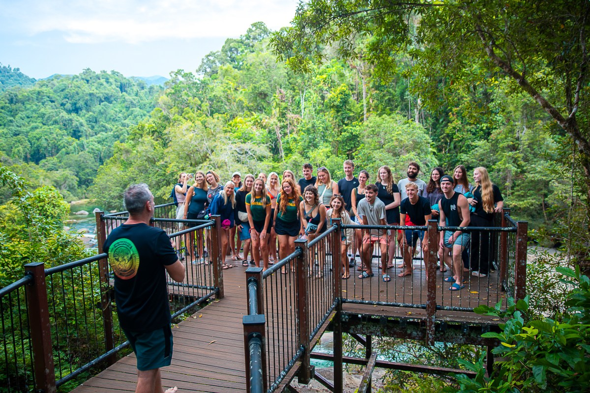 A group of people posing for a photo on a wooden deck in a lush forest setting.